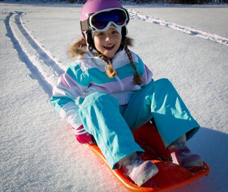 Child with toboggan sled on winter hill